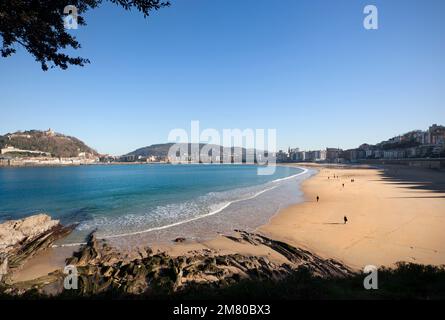 Donosti, Spanien-22. Dezember 2014: An sonnigen Tagen nutzen die Einwohner von Donosti die Gelegenheit für einen Spaziergang am Strand La Concha Stockfoto