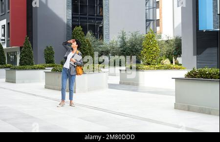 Frau mit Rucksack und Laptop, die durch moderne Gebäude des Business Centers spaziert Stockfoto