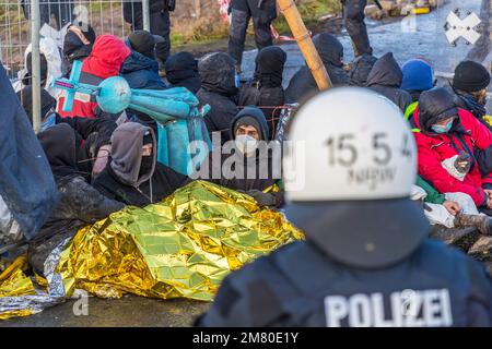 Sitzblockaden auf der Zufahrtsstraße sind die ersten, die aufgelöst werden. Klimaschutzaktivisten haben sich im deutschen Braunkohlendorf Lutzerath in Nordrhein-Westfalen verbarrikadiert. Die Aktivisten besetzen das Dorf seit mehr als zwei Jahren, um zu verhindern, dass es vom Erdboden verschwindet, wie es in einem von politischen Führern ausgehandelten Abkommen vereinbart wurde. Das Energieunternehmen RWE baut dort Braunkohle ab, die Aktivisten für die globale Erwärmung und die CO2-Verschmutzung verantwortlich machen. Heute früh begann die Polizei, das Dorf zu evakuieren. Stockfoto