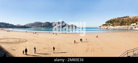 Donosti, Spanien-22. Dezember 2014: An sonnigen Tagen nutzen die Einwohner von Donosti die Gelegenheit für einen Spaziergang am Strand La Concha Stockfoto