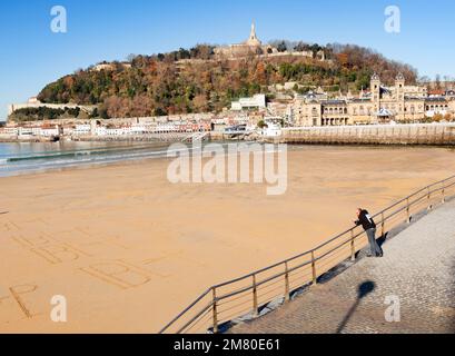 Donosti, Spanien-22. Dezember 2014: An sonnigen Tagen nutzen die Einwohner von Donosti die Gelegenheit für einen Spaziergang am Strand La Concha Stockfoto