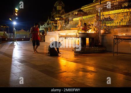 Tägliches Leben Myanmar - Menschen bei Nacht in der Nähe eines goldenen Tempels im Dorf Dawei. Dawei, Stockfoto