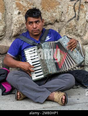 Ein Mann spielt Akkordian auf der Straße für Spenden in Oaxaca, Mexiko. Stockfoto