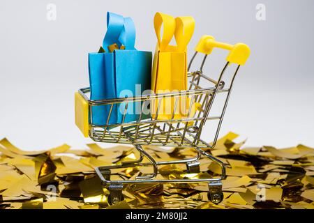Einkaufstaschen im Karren auf Pailletten auf weißem Hintergrund. Das Konzept des Verkaufs. Stockfoto