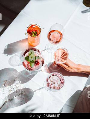 Verschiedene Sorten Wein und Wein Cocktails in Gläsern, zubereitet für die Verkostung auf einem weißen Tisch im Innenbereich Stockfoto