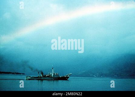 Steuerbordbalken-Ansicht des Panzerlandeschiffes USS FRESNO (LST 1182), das unter einem Regenbogen aus dem Hafen ausläuft. Die FRESNO bereitet sich auf Operationen mit der 7.-Flotte vor. Basis: Subic Bay Country: Philippinen Stockfoto