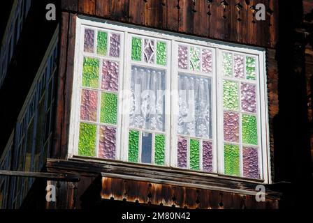 Buntes Gitterfenster, Fensterglas in einem alten Holzhaus Stockfoto