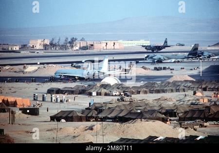 Ein Flugzeug der Air Force C-130 Hercules landet während der multinationalen Übung Bright Star '83 in einem Flugzeugstadion namens Kairo West. Im Vordergrund werden ein Luftfahrzeug des Typs E-3A Sentry Airborne Warning and Control System (AVACS) und eine B-52 Stratofortress gewartet. Betreff Operation/Serie: BRIGHT STAR '83 Basis: Kairo Land: Ägypten (EGY) Stockfoto