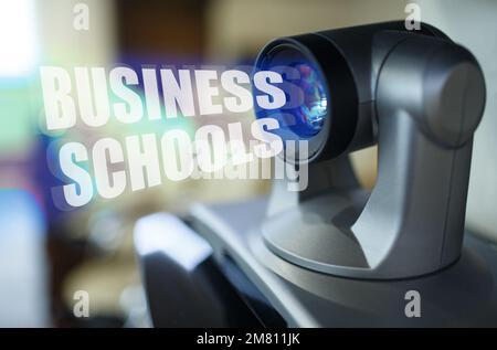 Geschäfts- und Lernkonzept. Ein blauer Strahl leuchtet vom Projektor im Inneren, der Aufschrift "Business Schools". Im Hintergrund ist ein verschwommenes Bild Stockfoto