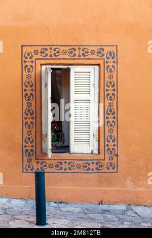 Wunderschöne alte Details eines Hausfensters mit handgefertigten Gemälden rund um das Fenster, in Ano Poli, dem traditionellen Viertel von Thessaloniki, Griechenland. Stockfoto