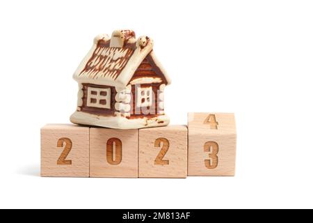 Holzwürfel mit der Aufschrift 2023 verwandeln sich in 2024 und Haus auf weißem Hintergrund Stockfoto