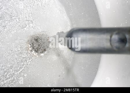 Wasser fließt aus dem Wasserhahn über der Ablauföffnung in der Wanne Stockfoto