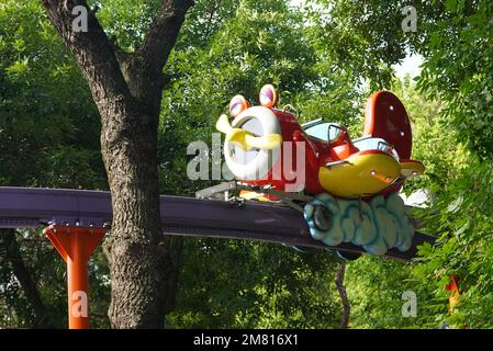 Kinderspielzeugflugzeug-Fahrzeug, das sich im Vergnügungspark in Bukarest auf der Schiene in der Luft bewegt Stockfoto