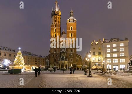 Basilika St. Marys Krakau im Dunkeln beleuchtet; Krakauer Marktplatz im Winterschnee zu Weihnachten, Krakauer Altstadt, Krakau Polen Stockfoto