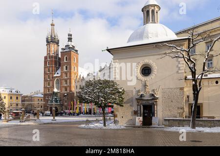 Der Krakauer Marktplatz im Winter; die Marienkirche auf der Rückseite und die romanische Kirche St. aus dem 11. Jahrhundert Wojciech vorne. Krakauer Altstadt. Stockfoto