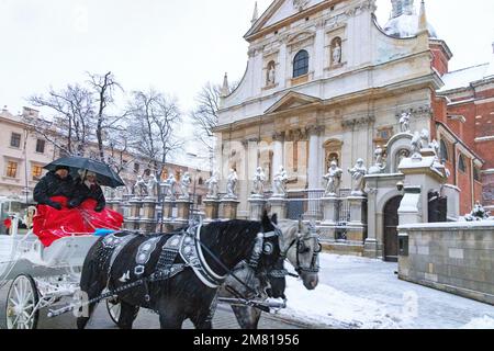 Krakauer Tourismus - ein Pferd und eine Kutsche passieren die Kirche der Heiligen Peter und Paul im Winterschnee, Krakau Polen Europa Stockfoto