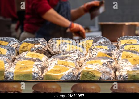 Buc-ee's Angestellter hackt Fleisch hinter einem Wärmestablett voller gegrillter Sandwiches bei Buc-ee's in Warner Robins, Georgia. (USA) Stockfoto