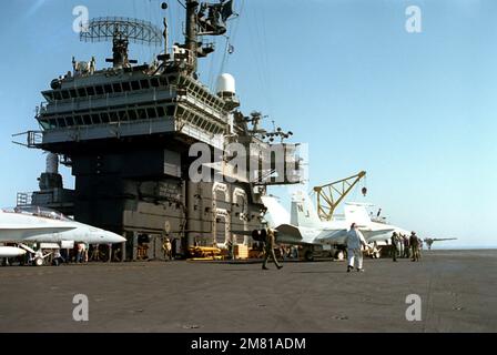 Ein Blick auf die Inselstruktur an Bord des Flugzeugträgers USS KITTY HAWK (CV 63). Zwei F/A-18 Hornet-Flugzeuge vom Strike Fighter Squadron 125 (VFA-125) parken auf dem Deck. Basis: USS Kitty Hawk (CV 63) Stockfoto