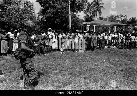 Ein Marine bewacht eine Gruppe Zivilisten, nachdem er mit dem Bataillonsmannschaftsteam A während der Operation "URGENT WUT" angekommen ist. Die Marines wurden aus Grenada eingesetzt, als sie darüber informiert wurden, dass Mitglieder der Revolutionsarmee der Völker auf der Insel waren. Betreff Operation/Serie: URGENT FURY Base: Carriacou Island Country: Grenada (GRD) Stockfoto