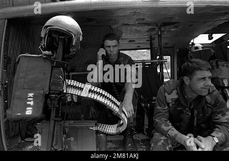 Zwei Marines sitzen an Bord eines UH-1 Iroquois Helikopters, nachdem sie mit dem Bataillon-Landeteam A während der Operation URGENT FURY angekommen sind. Die Marines wurden aus Grenada eingesetzt, als sie erfuhren, dass Mitglieder der Revolutionsarmee hier waren. Ein M60-Maschinengewehr ist auf dem Hubschrauber montiert. Betreff Operation/Serie: URGENT FURY Base: Carriacou Island Country: Grenada (GRD) Stockfoto