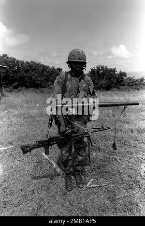 Ein Marine zeigt einen beschlagnahmten sowjetischen RPG-2 Raketenwerfer und ein leichtes Maschinengewehr von Bren, nachdem er mit Bataillon Landing Team A während der Operation Urgent Fury angekommen ist. Sie wurden aus Grenada eingesetzt, als sie darüber informiert wurden, dass Mitglieder der Revolutionsarmee der Völker hier auf der Insel sind. Betreff Operation/Serie: URGENT FURY Base: Carriacou Island Country: Grenada (GRD) Stockfoto