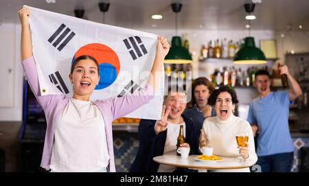 Eine Gruppe von glücklichen Freunden mit der Flagge von Südkorea, die den Sieg ihrer Lieblingsmannschaft in der Bierstube feiern Stockfoto