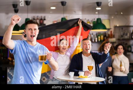 Begeisterte deutsche Fans brüllen vor Freude in der Bierstube. Sieg Deutschlands Stockfoto