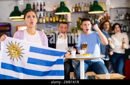 Fans mit der Flagge Uruguays feiern den Sieg ihrer Lieblingsmannschaft in der Bierstube Stockfoto