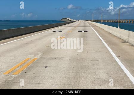 Reisen Sie mit dem Auto in Florida, wunderschöne Aussicht auf den Long Overseas Highway mit Autos, das Meerwasser des Golfs von Mexiko und Strommasten auf beiden Seiten der Straße, Stockfoto