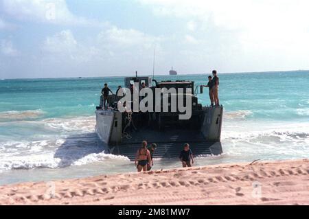 Marines und Matrosen bereiten sich darauf vor, Fahrzeuge während der Operation KERNAL BLITZ von einem mechanisierten Landungsfahrzeug (LCM Mark 8) zu entladen. Betreff Betrieb/Serie: KERNAL BLITZ Base: Bellows Beach, Oahu Bundesstaat: Hawaii (HI) Land: Vereinigte Staaten von Amerika (USA) Stockfoto