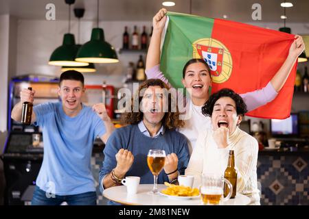 Fans mit der Flagge Portugals feiern den Sieg ihrer Lieblingsmannschaft in der Bierstube Stockfoto