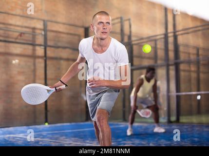 Konzentrierter Paddle-Tennisspieler, der sich auf die Vorhand vorbereitet Stockfoto