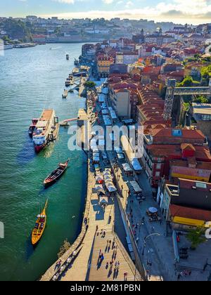 Ribeira-Ufer in hellem Sonnenlicht, Blick von oben, Tourboote, Menschen, die in Cafés spazieren gehen und sitzen, Porto, Portugal Stockfoto