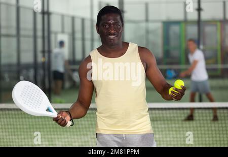 Fröhlicher afroamerikanischer Paddeltennisspieler in der Halle Stockfoto