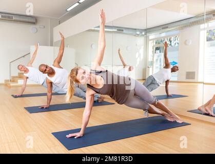 Junge Erwachsene Frau, die mit der Gruppe Yoga praktiziert Stockfoto