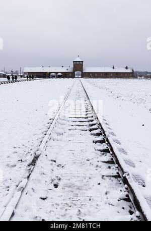 Auschwitz-Birkenau-Konzentrationslager; düsteres Eingangstor und Eisenbahnlinie im Winterschnee; Auschwitz, Oswiecim Polen; Todeslager der Nazis im Zweiten Weltkrieg. Stockfoto