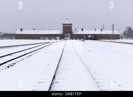 Konzentrationslager Auschwitz Birkenau; düsteres Eingangstor und Bahnlinie im Winterschnee; Auschwitz, Oswiecim Polen; UNESCO-Weltkulturerbe. Stockfoto