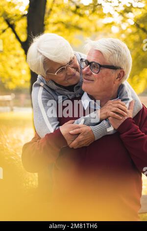 Liebendes Seniorenpaar, das im Herbstpark umarmt. Hochwertiges Foto Stockfoto