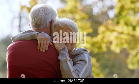 Pensionierte grauhaarige Frau umarmt ihren Mann draußen. Hochwertiges Foto Stockfoto