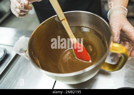 Zubereitung von Brownies oder Cupcakes. Flüssiger Teig. Geschmolzene Schokolade in einer Schüssel mit Spatel. Hochwertiges Foto Stockfoto