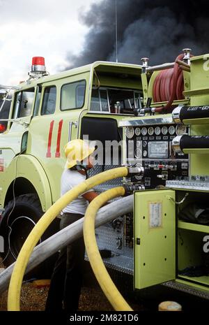 Ein Feuerwehrmann der 3. Einheit Bauingenieurwesen stellt die Hauptstromleitung am Feuerwehrauto Nr. 11 auf. Feuerwehrleute kämpfen gegen einen Brand, der die USA verschlungen hat Anlage 3., Vorratsgeschwader, überdachter Lagerbereich 11A. Der Schaden wurde auf $3 Millionen Dollar geschätzt. Stützpunkt: Clark Air Base Staat: Luzon Country: Philippinen (PHL) Stockfoto