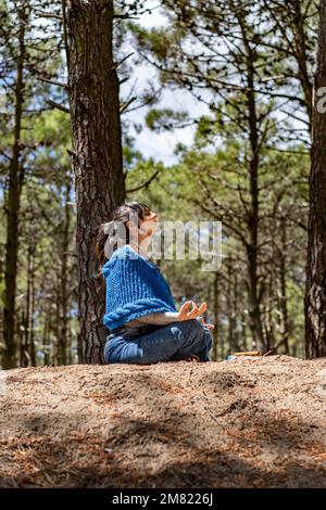 Seitenansicht einer Frau, die sich im Wald die Hände zusammenschlägt. Stockfoto