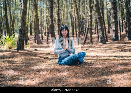 Eine Frau, die sich die Hände im Wald zusammenschlägt. Namaste-Pose. Stockfoto