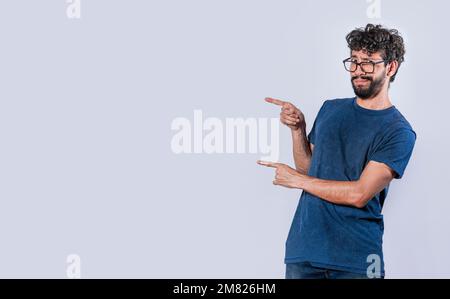Lächelnder, gutaussehender Mann, der zwei Finger zur Seite zeigt, freundlicher, gutaussehender Mann, der zwei Finger zur Seite zeigt, Konzept eines jungen Mannes, der auf einen zeigt Stockfoto