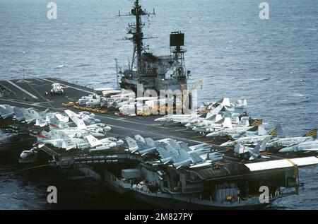Erhöhte Sicht auf das Cockpit des Flugzeugträgers USS MIDWAY (CV 41). Zu den Flugzeugen auf dem Deck gehören von vorne nach hinten (rechte Seite): F-4 Phantom II, EA-6B Prowler, A-6 Intruder und E-2 Hawkeye. Zu den Flugzeugen auf der linken Seite gehören Die Maschinen A-7 Corsair II und A-6 Intruder. Im Hintergrund ist ein SH-3 Sea King Hubschrauber zu sehen. Land: Pazifik (POC) Stockfoto