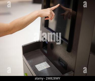 Gesichtslose Frau mit Touchscreen-Geldautomat. Stockfoto