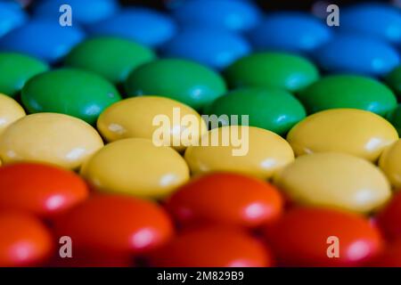 Nahaufnahme von bunten Süßigkeiten, die flach liegen. Hintergrund für Regenbogenbonbons. Regenbogen-Dragee. Süßigkeiten, Kaugummi, Knöpfe Stockfoto