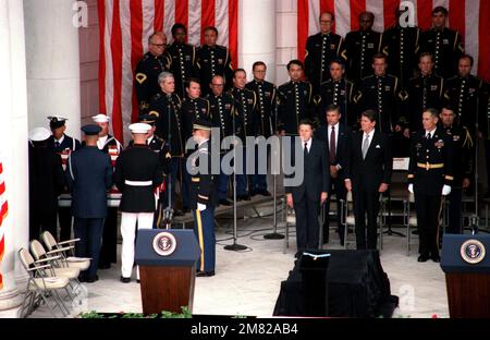 Ein Team aus dem Sarg bringt den Sarg des unbekannten Soldaten aus dem Staatsbeerdigungsdienst auf dem Nationalfriedhof Arlington. Der Soldat wird am Grab der Unbekannten begraben. Der Chorus der US-Armee steht hinter Präsident Reagan und Verteidigungsminister Caspar Weinberger. Basis: Arlington Bundesstaat: Virginia (VA) Land: Vereinigte Staaten von Amerika (USA) Stockfoto