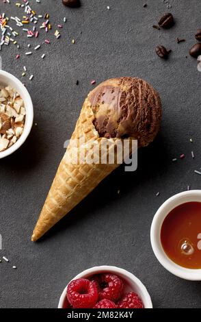 Karamell- und Schokoladeneis in Waffelform auf dunkelgrauem Hintergrund, Draufsicht Stockfoto