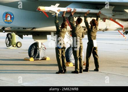 Eine 33. taktische Kampfhubschrauber-Crew lädt eine AIM-9 Sidewinder-Rakete auf den Flügelpylon eines F-15 Eagle-Flugzeugs, während die Luft-Luft-Waffen William Tell '84 treffen. Betreff Operation/Serie: WILLIAM TELL '84 Basis: Tyndall Luftwaffenstützpunkt Bundesstaat: Florida (FL) Land: Vereinigte Staaten von Amerika (USA) Stockfoto